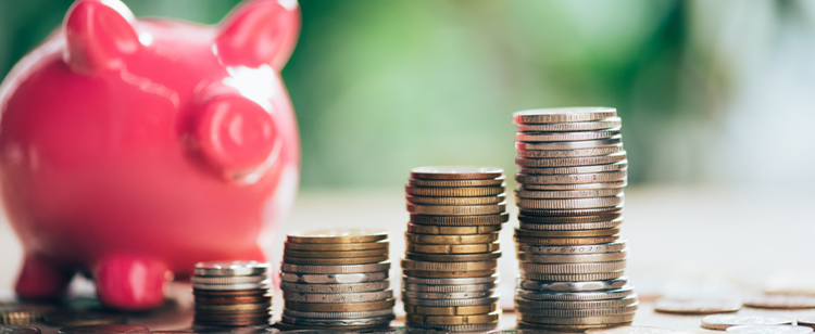 Stacked coins and pink piggy bank, close-up view